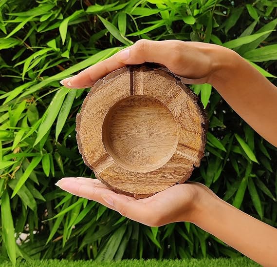Wooden bowl held between two hands with a green leafy background